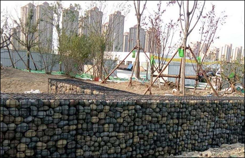 Welded mesh boxes filled with stone or rock forming a fencing barrier for sites
